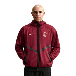 A person wears a maroon Nike Chivas 26/27 Third Jacket, a zip-up hooded piece with a mesh texture and gold logos on the chest.