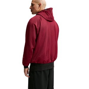 A person viewed from the back wearing a red, mesh-textured, official Nike Chivas 26/27 Third Jacket with black cuffs.