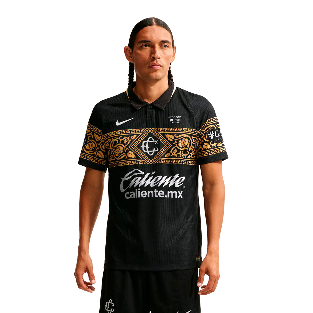 A man wears a black Nike Chivas 26/27 Match Third Autenthic Jersey featuring a gold ornate pattern across the chest and sleeves, sponsor logos, and a polo-style collar.