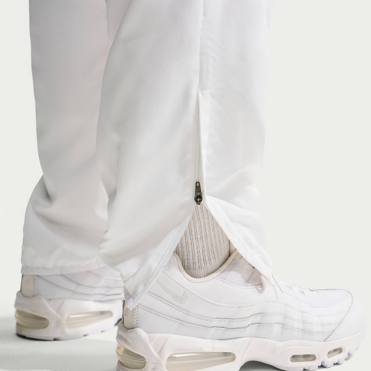 White Nike Premier Repel Pants with a zippered vent at the ankle, worn with white sneakers as part of an official soccer gear game-day look.