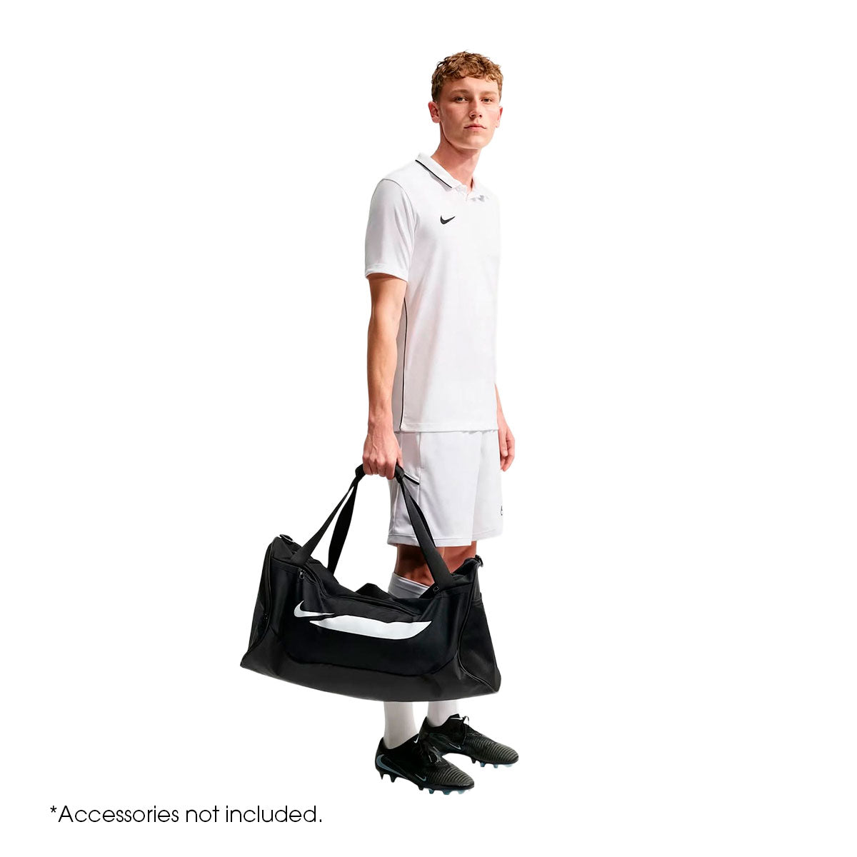 A man in official soccer gear holds a black Nike Academy Duffel Bag with a large white graphic on the side, completing his game-day look.