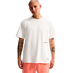 A man wearing a white Nike Sportswear T-Shirt with a small patch on the hem.