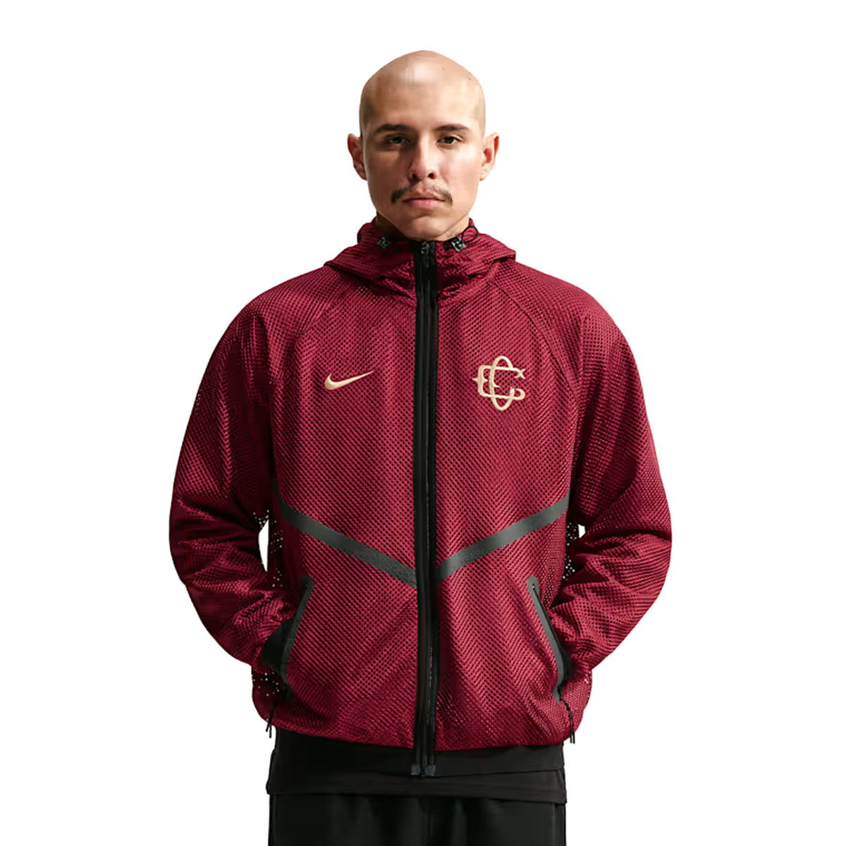 A person wears a maroon Nike Chivas 26/27 Third Jacket, a zip-up hooded piece with a mesh texture and gold logos on the chest.