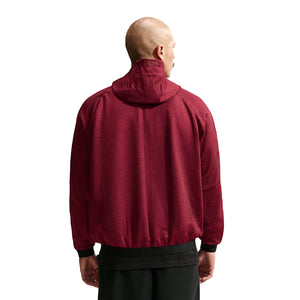 A person viewed from the back wearing a dark red, textured Nike Chivas 26/27 Third Jacket with black trim at the hem and cuffs, styled as official soccer gear.