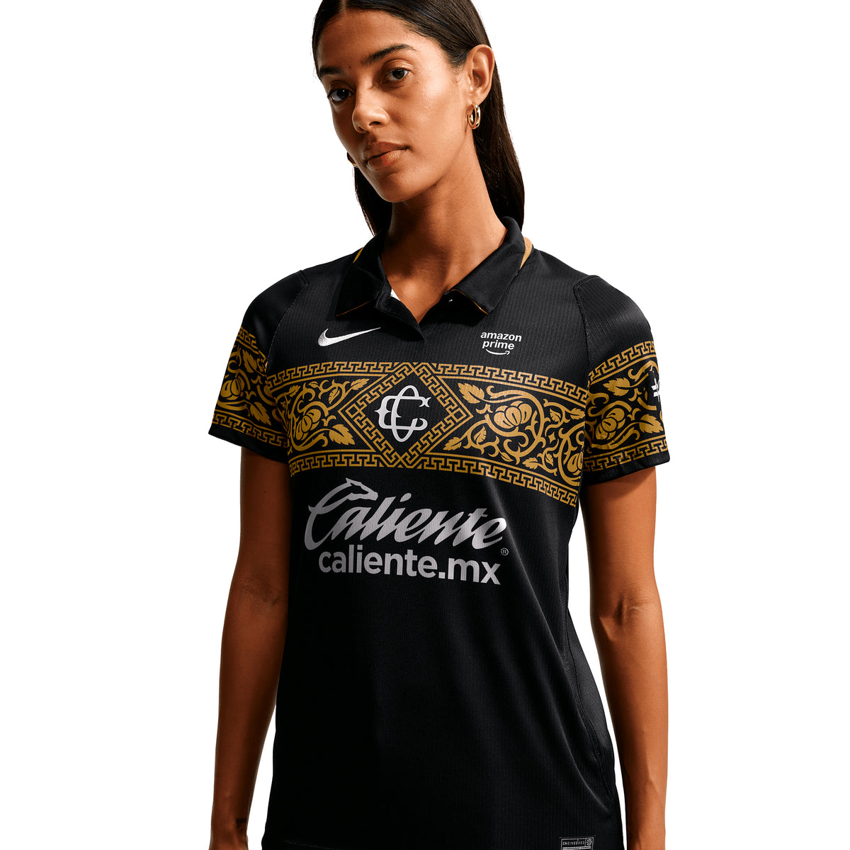 A person wearing a black Nike Chivas 26/27 Stadium Third Jersey, featuring a gold ornate pattern across the chest and white sponsor logos.