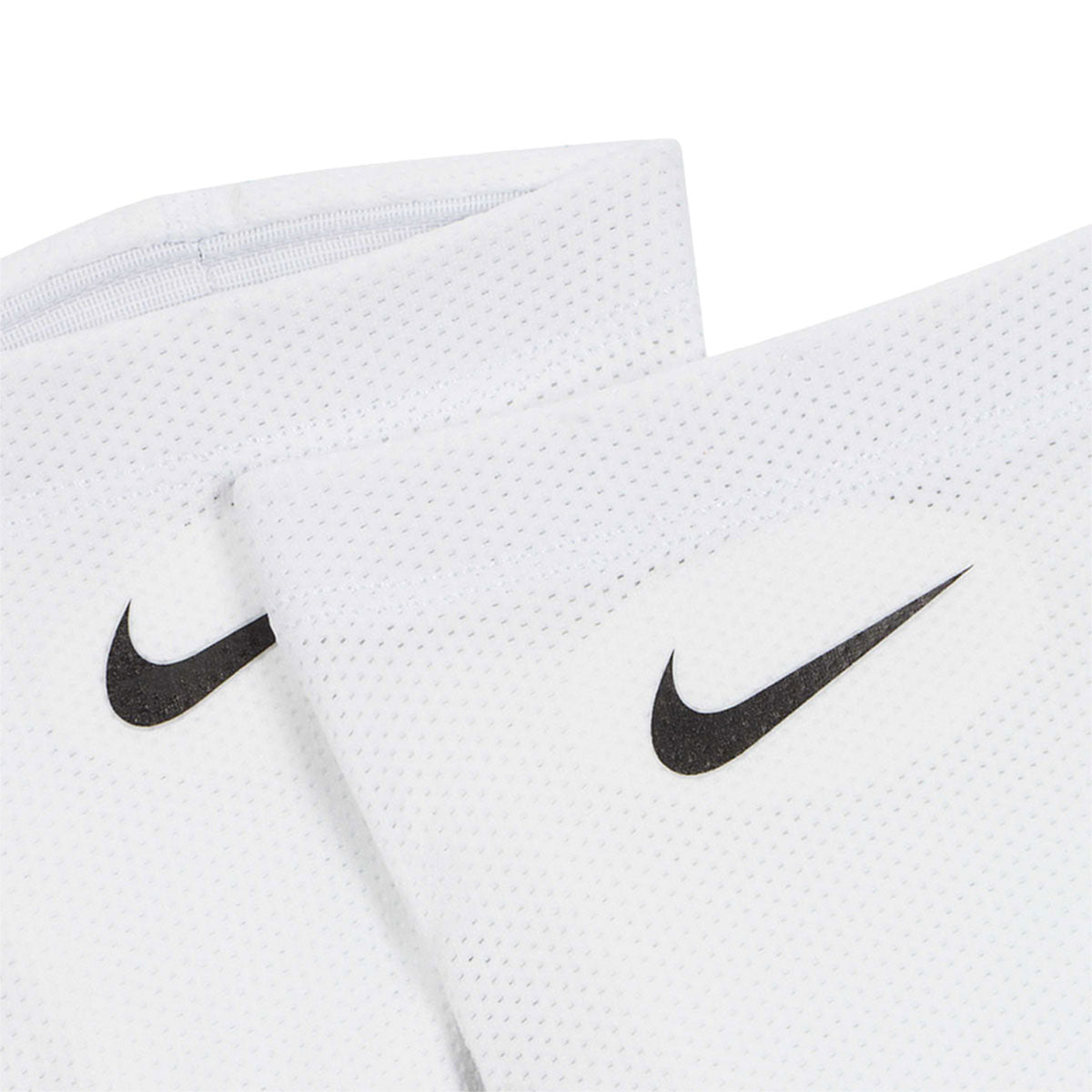 A pair of white Nike Nike Guard Lock Elite Sleeves featuring black swoosh logos, designed to complete an official soccer game-day look.